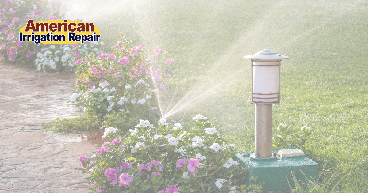 A Hunter sprinkler head in a backyard, set to spray mist mode, watering the green grass and flowers